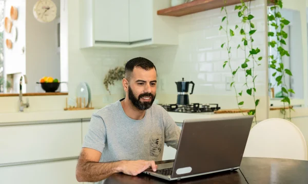 man with disability uses laptop in kitchen