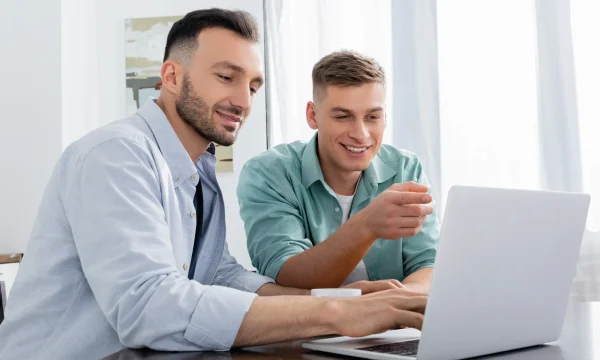 two men viewing online content on laptop