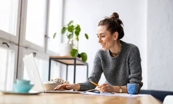 woman-smiling-while-working-and-taking-notes