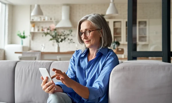 elder woman on couch scrolling on mobile
