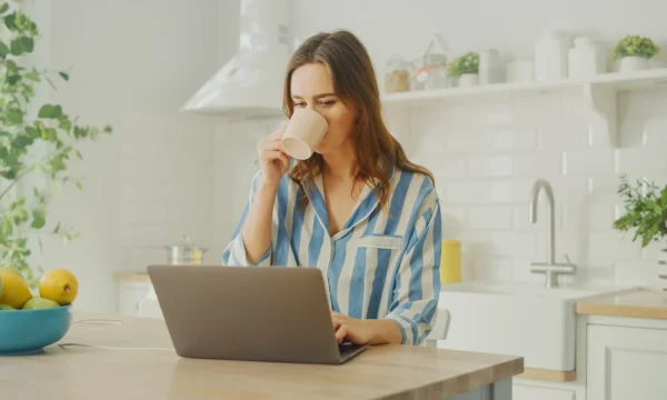 woman sips coffee while working on laptop