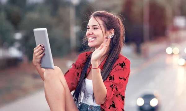 woman waving to a video call outdoors