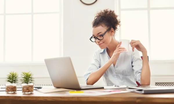 Woman gazes at laptop while holding mug